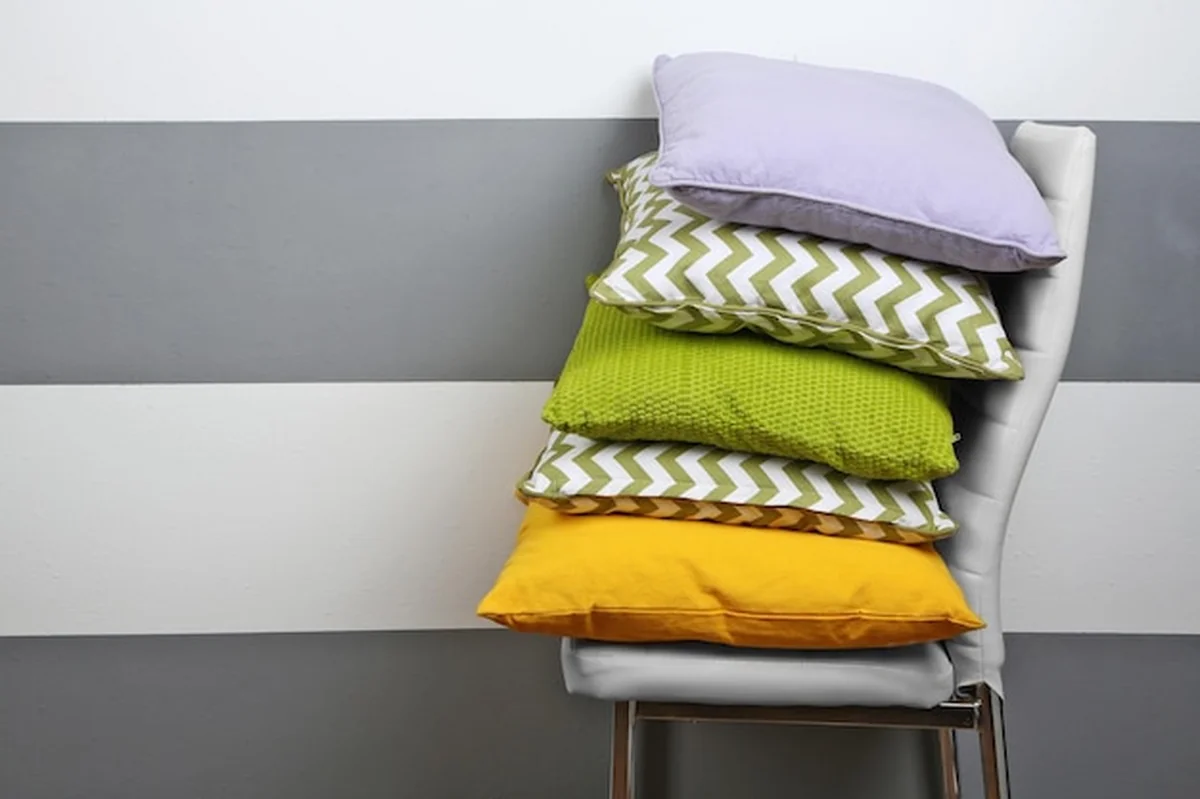 Kolorowe poduszki na krześle na szarym tle