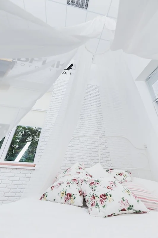 Białe łóżko z baldachimem w studiu fotograficznym