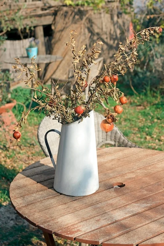 Drewniany stół z białym wazonem i granatami