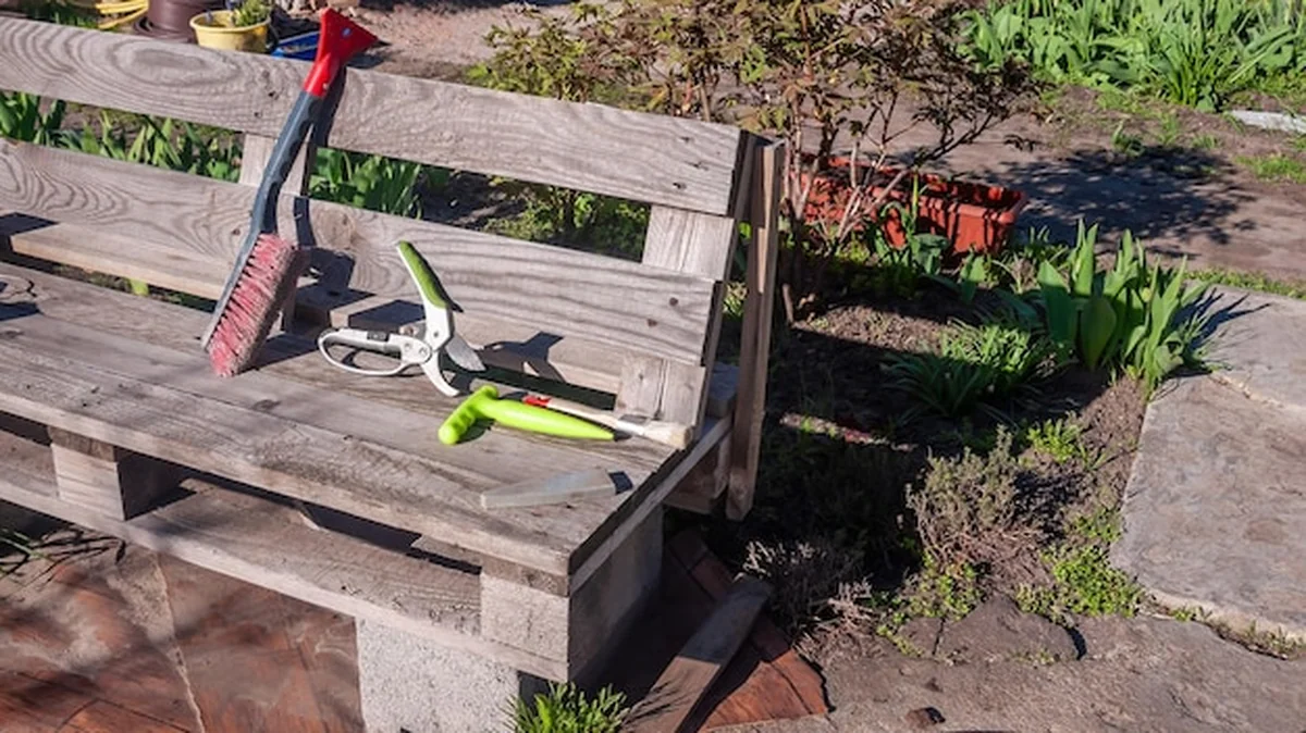 Drewniana ławka z narzędziami ogrodniczymi w oświetlonym ogrodzie