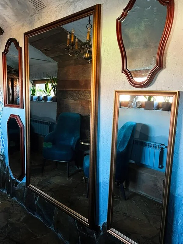 Rustyczne wnętrze z dużymi lustrami i niebieskimi krzesłami