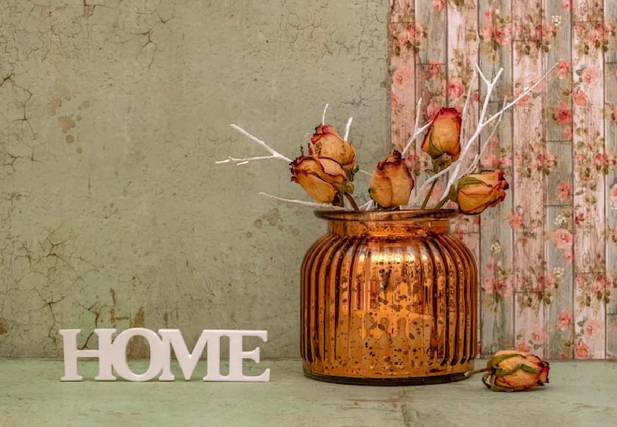 Martwa natura z suchymi kwiatami róży w szklanym wazonie na zielonym tle