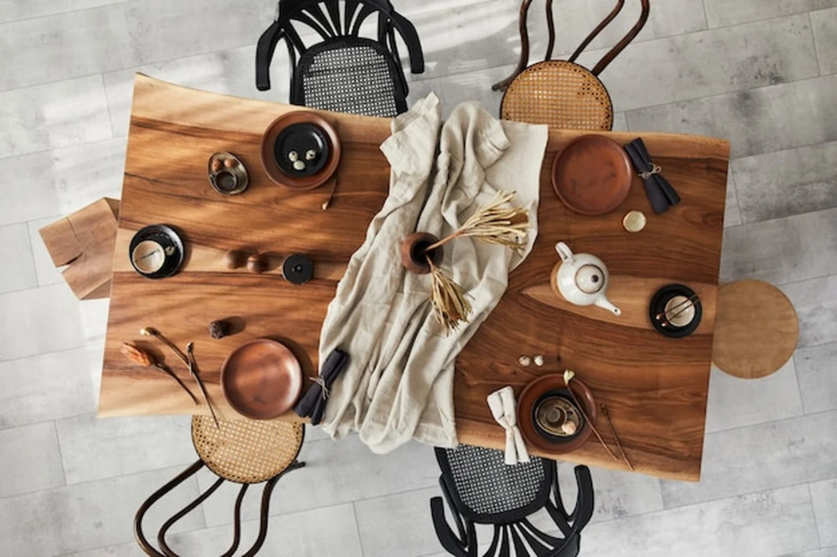 Aranżacja jadalni z drewnianym stołem orzechowym, retro krzesłami, zastawą stołową i dodatkami