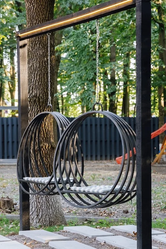 Nowoczesne huśtawki kołowe w ogrodzie otoczonym drzewami i światłem słonecznym