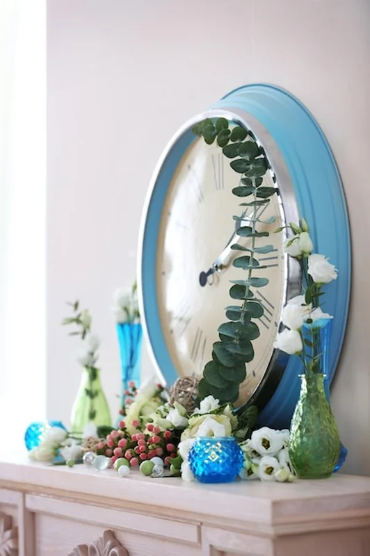 Zegar na komodę obok świeżych kwiatów