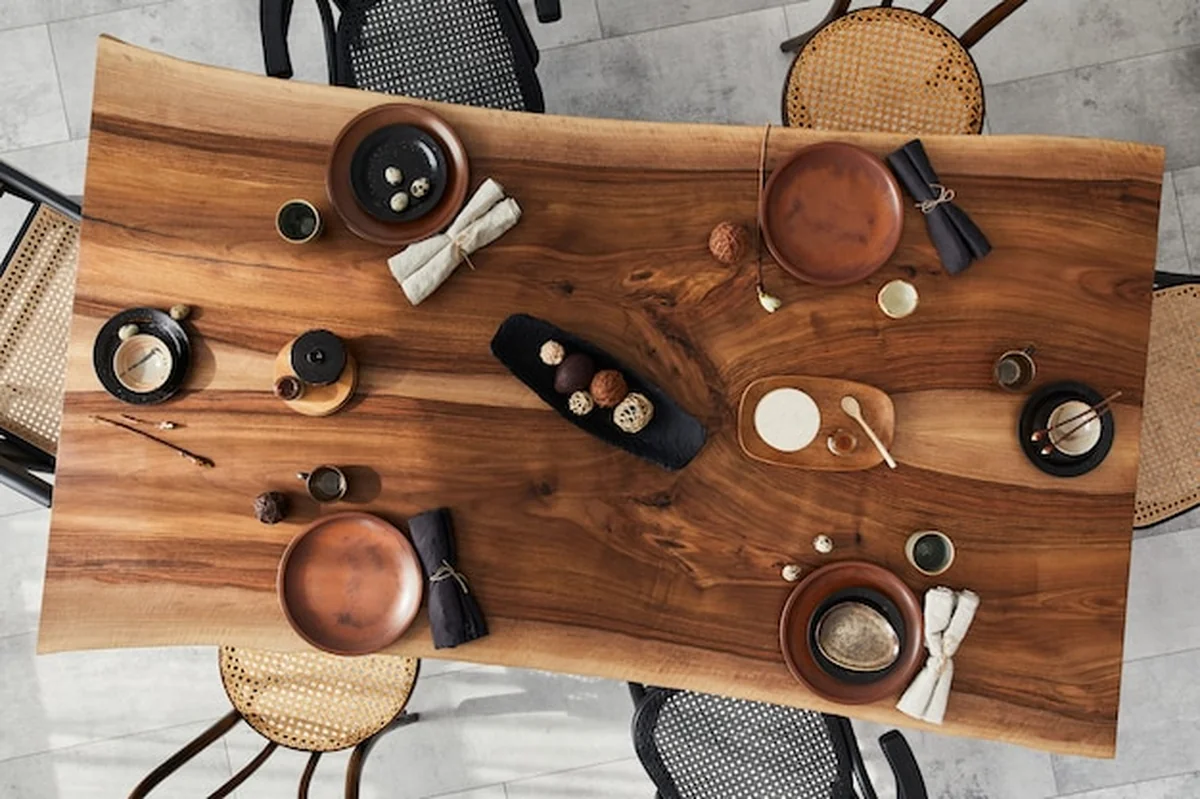 Aranżacja jadalni z drewnianym stołem orzechowym, krzesłami, zastawą stołową, talerzami, jedzeniem i dekoracją