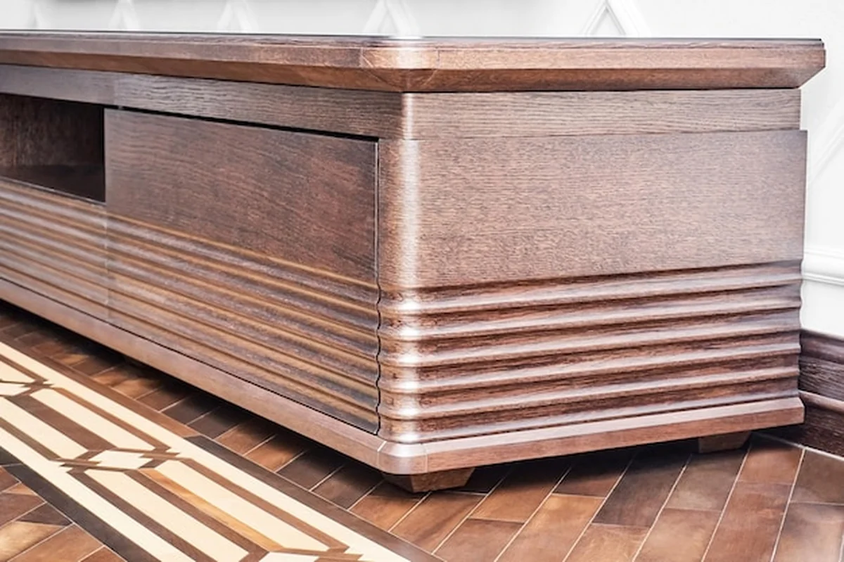 Szafka pod telewizor z drewna dębowego w kolorze ciemnobrązowym obok ściany