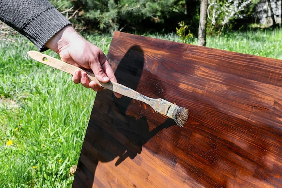 Mężczyzna maluje drewno pędzlem na stole