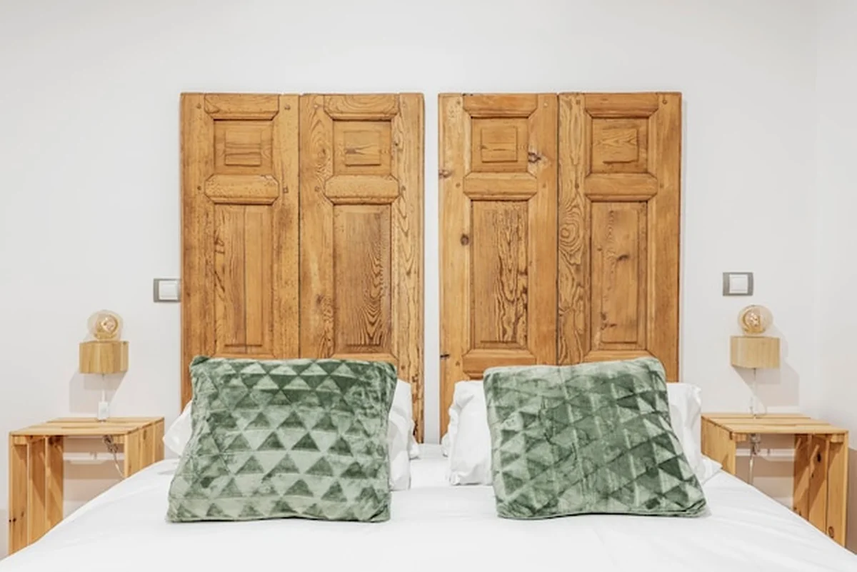 Sypialnia z podwójnym łóżkiem z rustykalnym zagłówkiem i drewnianymi okiennicami