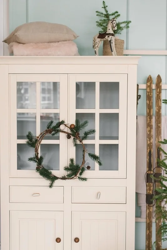 Biała szafa z dekoracjami i świątecznymi nartami w salonie domu