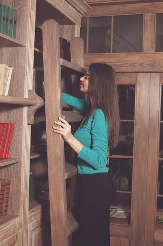 Piękna kobieta na półkach z książkami i schodami