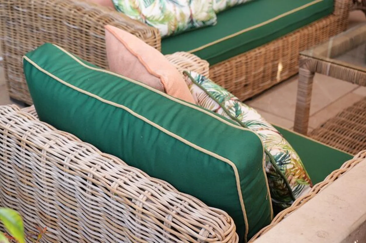 Stylowe meble z rattanu z zielonymi poduszkami na tarasie ogrodowym