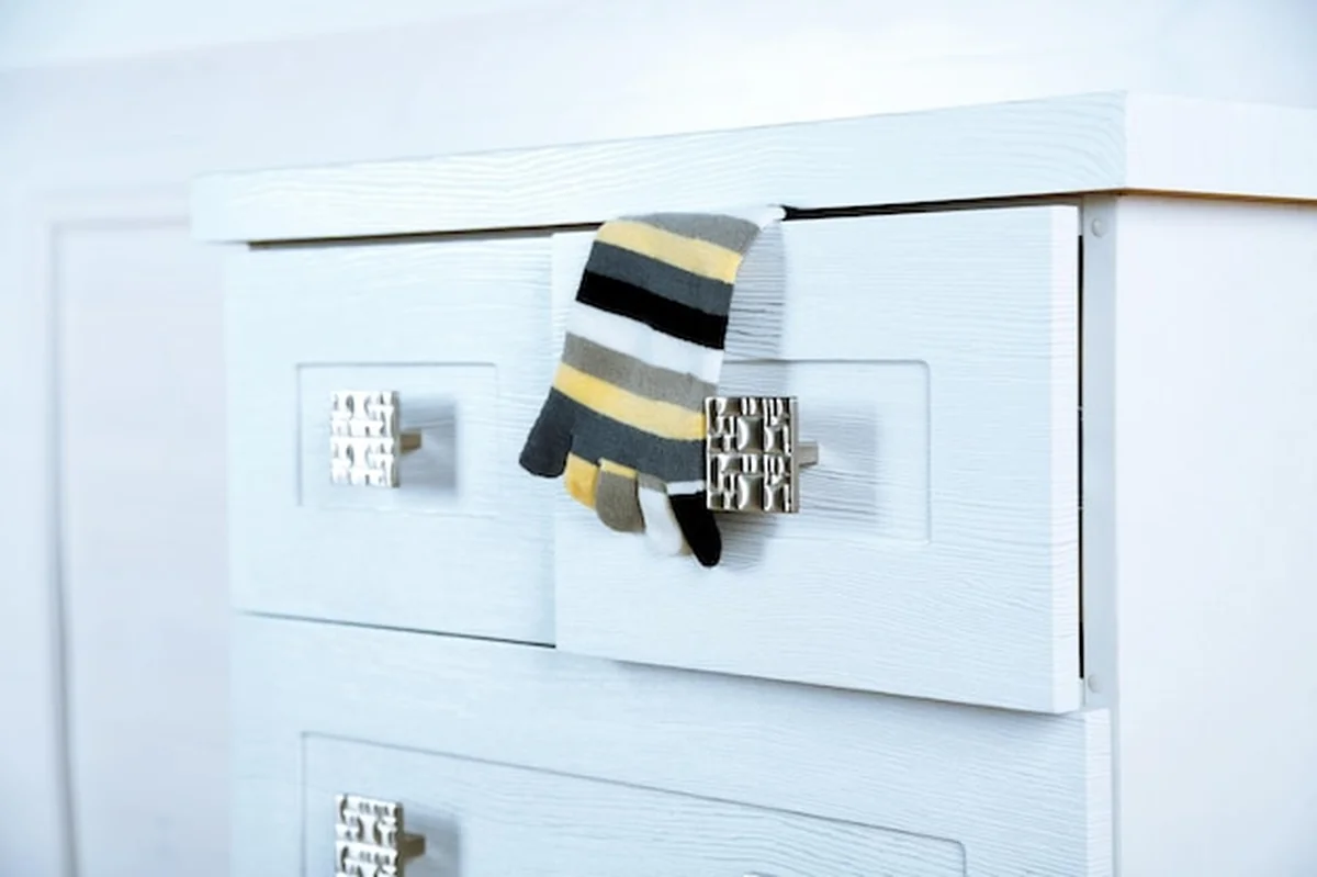 Biała drewniana komoda ze skarpetą w otwartej szufladzie