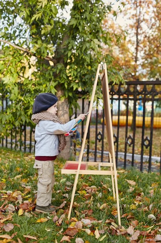 Małe dziecko w retro ubraniu siedzi uśmiechnięte w przyrodzie