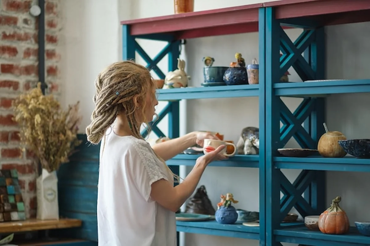 Garncarz układa ceramikę na regale drabinkowym