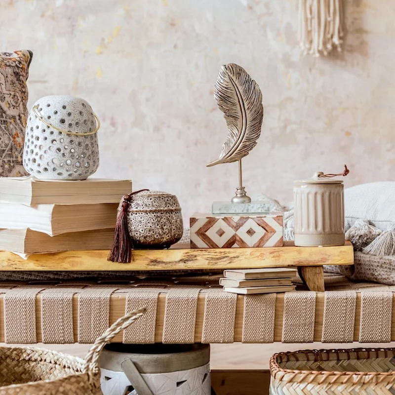 Nowoczesny orientalny salon z designerskim szezlongiem, makramą, poduszkami, drewnianą taca, książką i dekoracjami