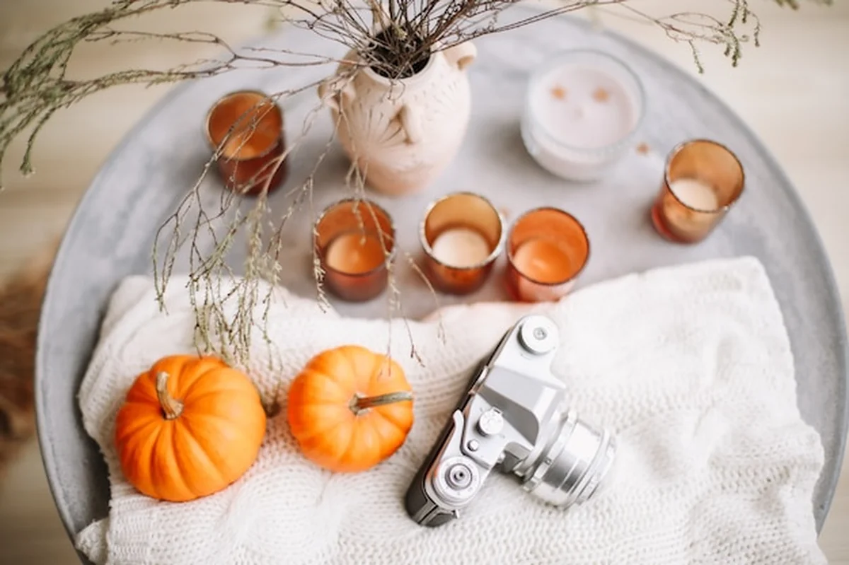 Jesienna kompozycja ze świeczkami dyniowymi, książką i suszonymi kwiatami