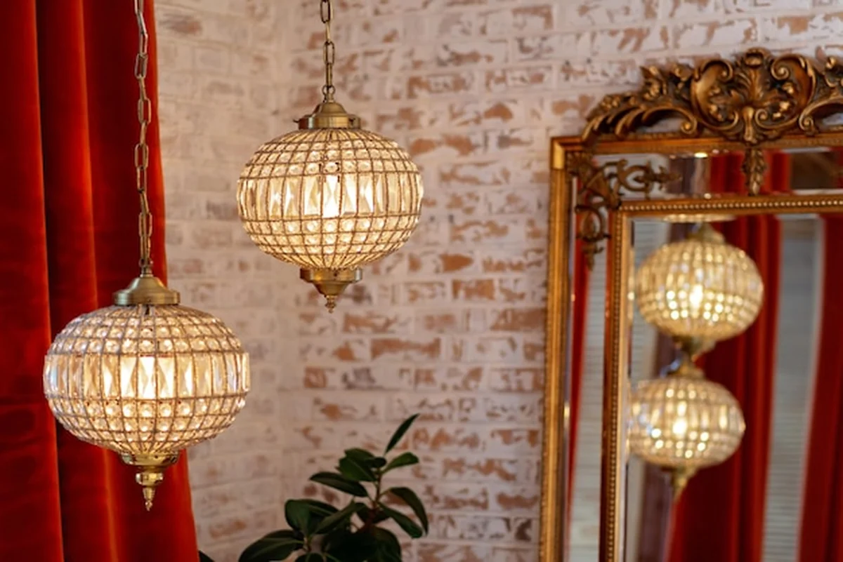 Wnętrze z lustrem vintage, bordowymi zasłonami i żyrandolami na ceglanej ścianie