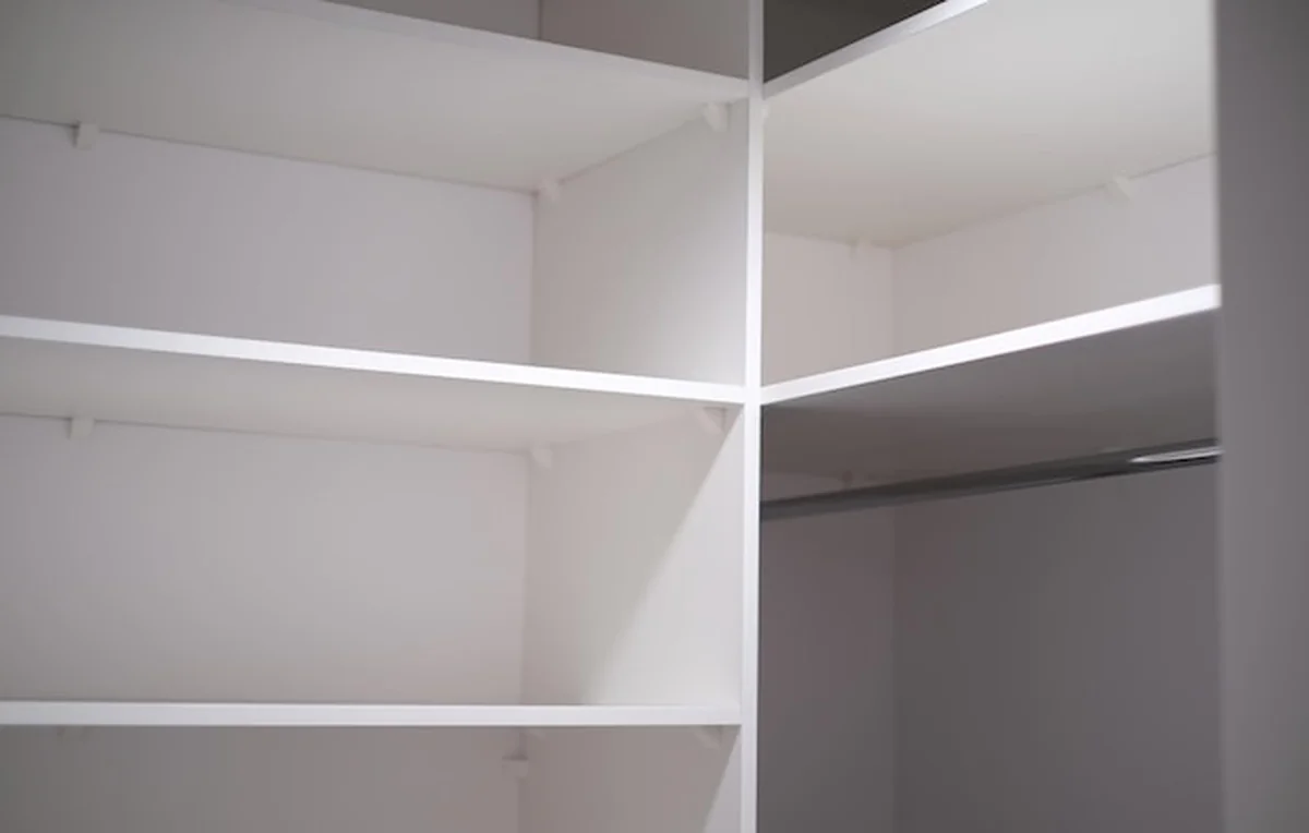 Biała szafa z pustymi półkami i nowoczesnym systemem przechowywania ubrań