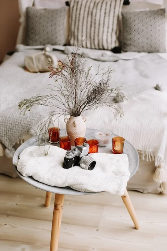 Nowoczesne wnętrze sypialni z łóżkiem z drewnianym baldachimem, kocem z poduszkami i stolikiem nocnym