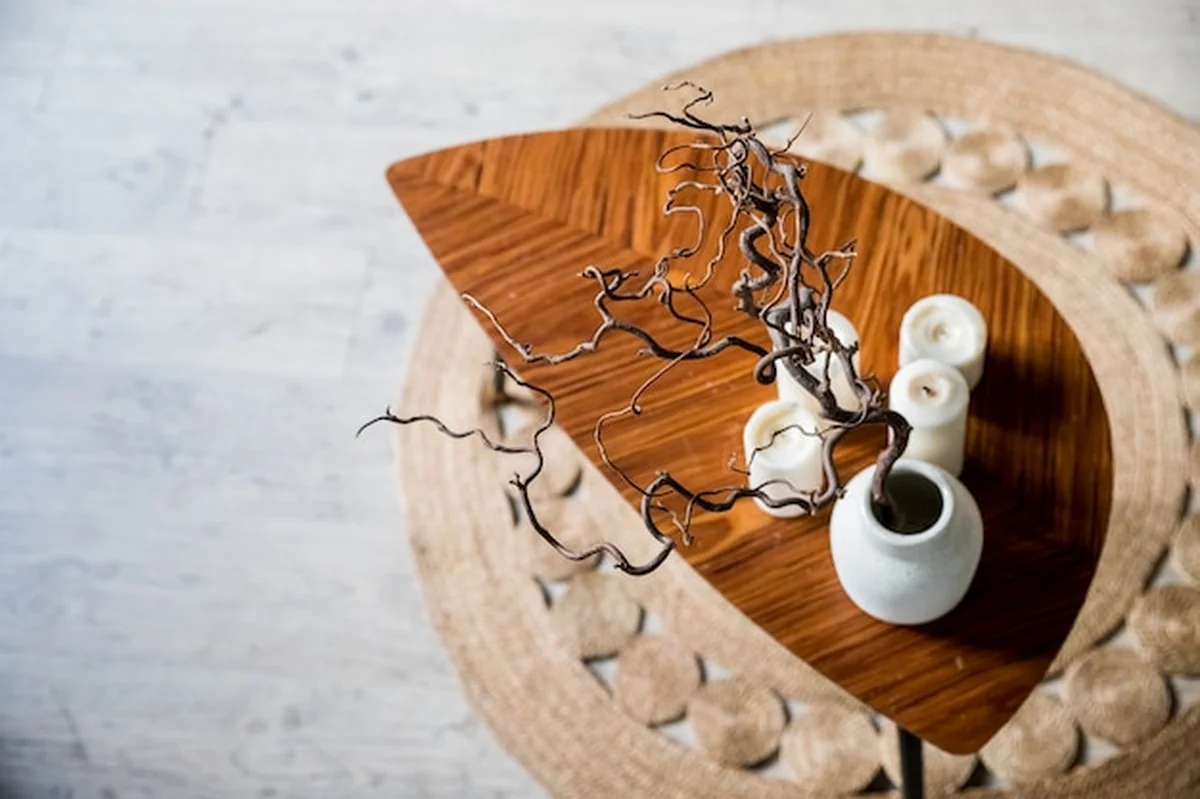 Drewniany stół z wazą ceramiczną na słomianym dywanie